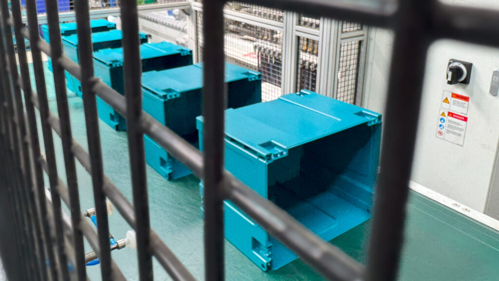 Conveyor belt moving along newly-made plastic components, showcasing robotics in manufacturing.